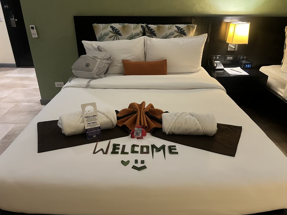 A made hotel bed with fresh linens and towels