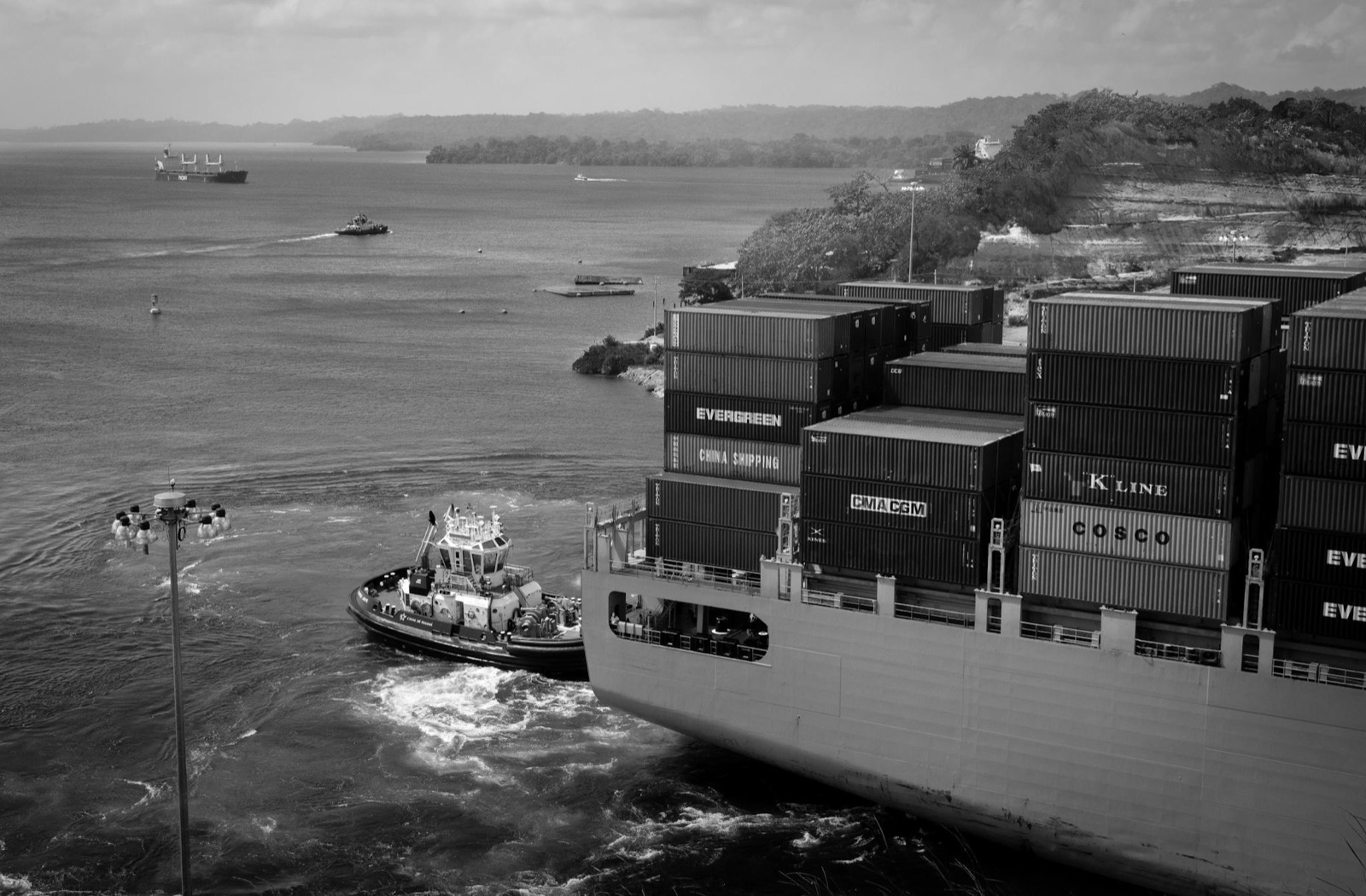 A container vessel guided by a tugboat, loaded with cargo