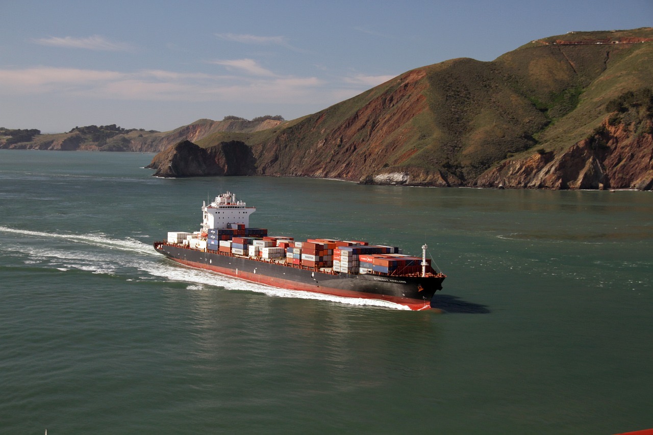 A loaded container ship underway along a coastal headland